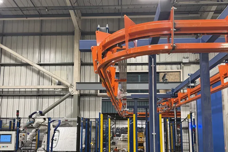 MCM Autotrack Power and Free conveyor system installed above robotic manufacturing equipment and safety guarding
